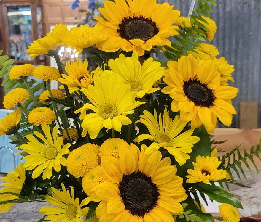 Sunflowers, yellow daisies and button poms in a smiling yellow mug